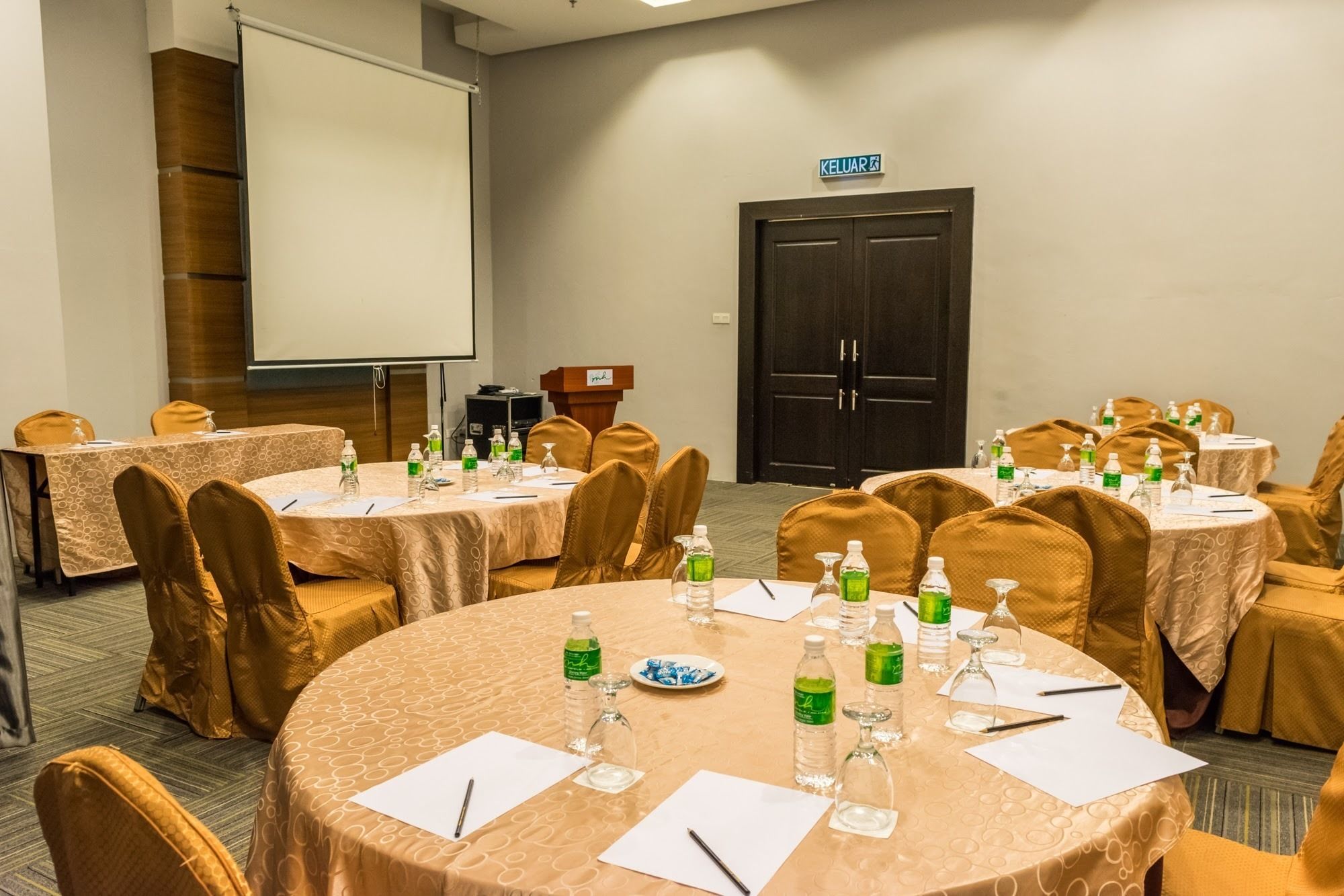 A conference room with multiple round tables, each set with chairs, water bottles, and nameplates.