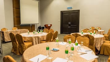 A conference room with multiple round tables, each set with chairs, water bottles, and nameplates.