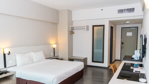 Une chambre d’hôtel moderne avec un grand lit, des tables de chevet, un bureau et un miroir.