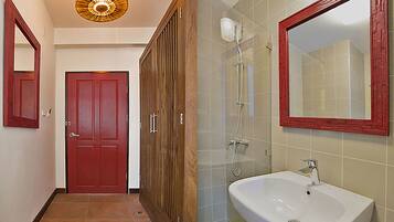 Un pasillo que conduce a un baño con puerta roja, armario de madera y lavamanos blanco con espejo sobre él.