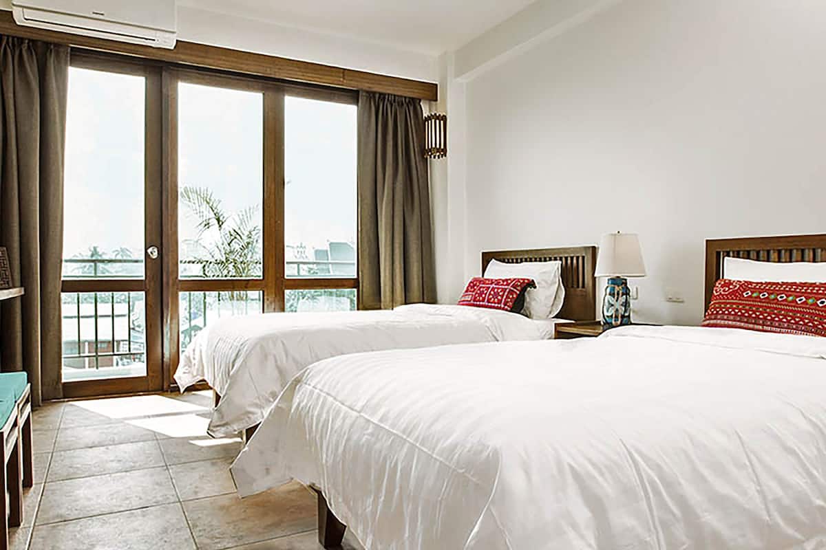 A hotel room with two beds, a balcony, and a view of the city.