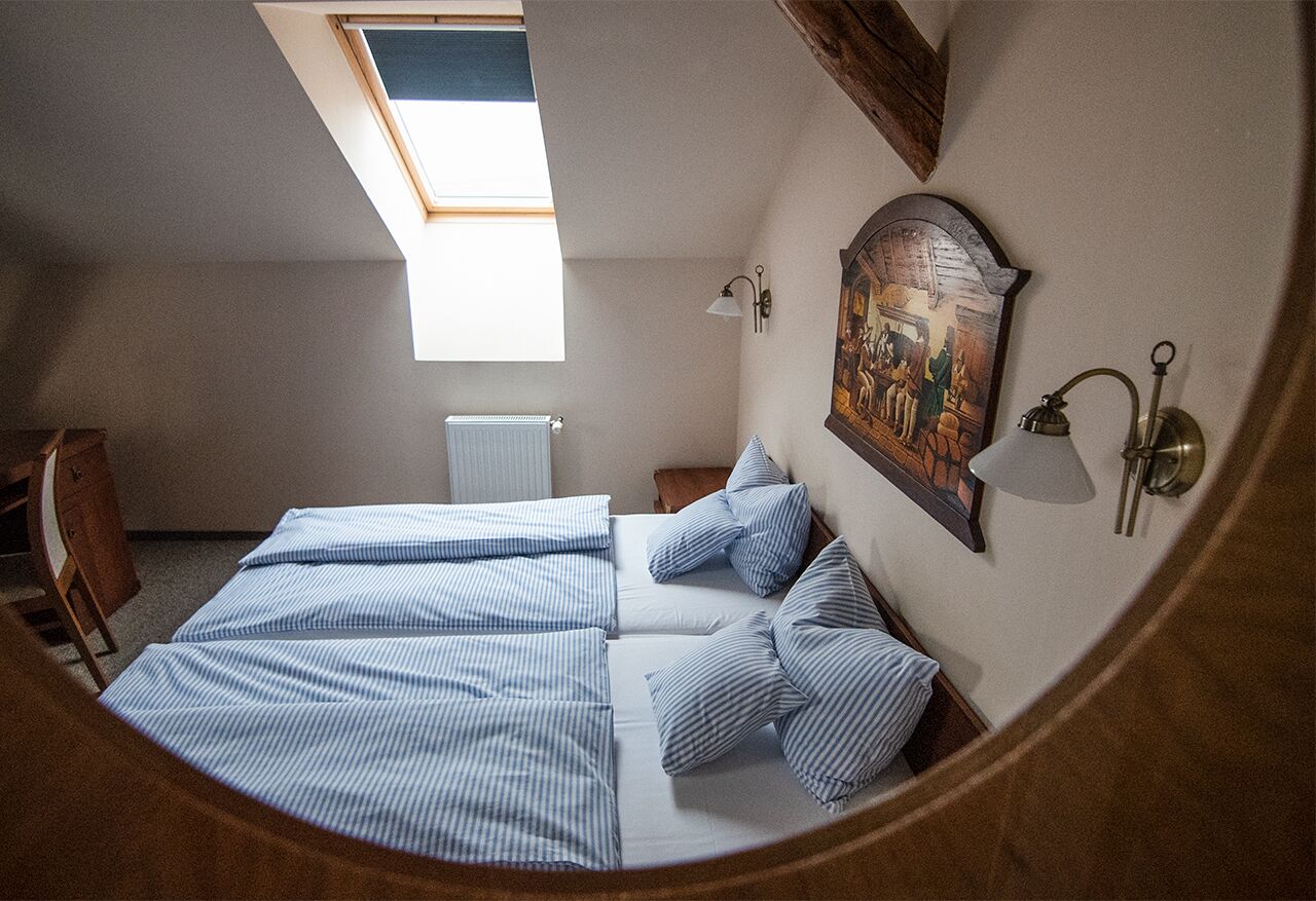Un dormitorio con cama, tragaluz, un cuadro y una mesita de noche.