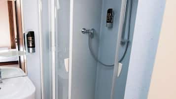 Un baño moderno con ducha de vidrio, un lavamanos blanco y un espejo.