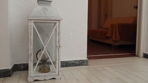 A white lantern with a glass enclosure, positioned against a textured wall.