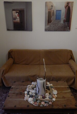 A brown sofa against a wall with two framed pictures above it. - Hotel Helmos (Naxos)
