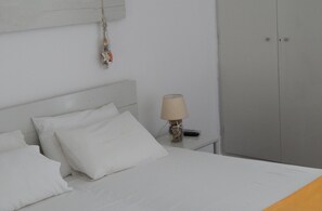 A bedroom with a bed, pillows, a lamp, and a wardrobe. - Hotel Helmos (Naxos)