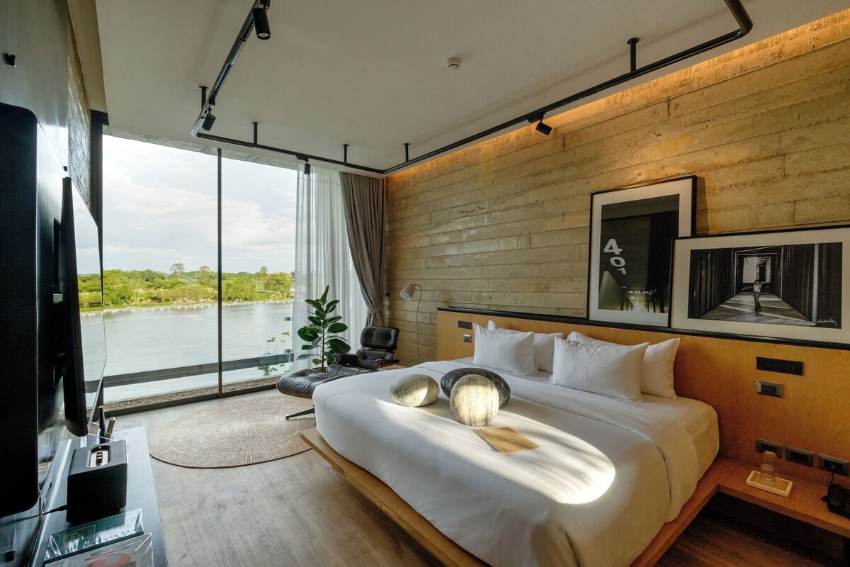 Une chambre d’hôtel moderne avec un grand lit, une vue sur un plan d’eau et un mur décoratif en bois.