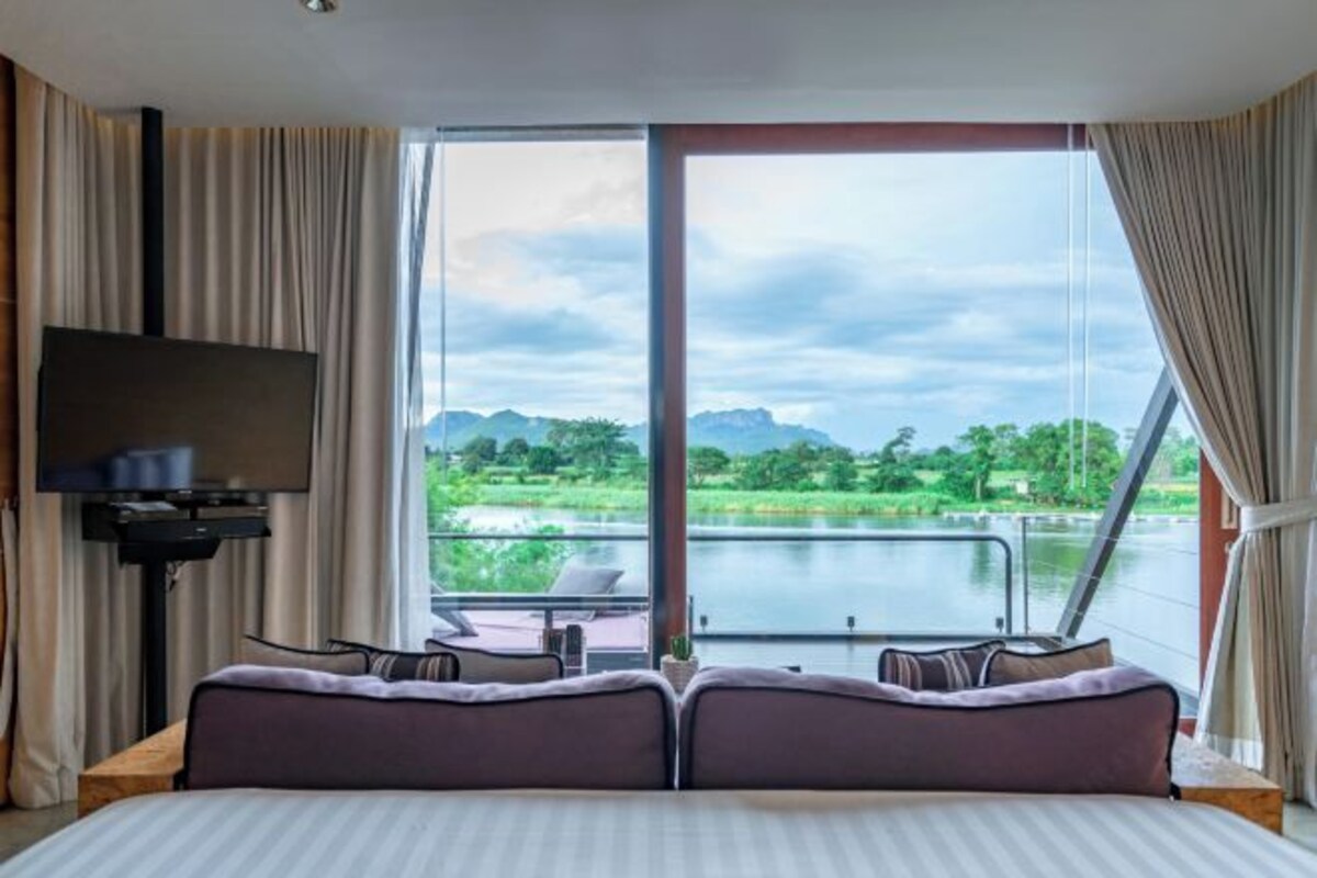 Une chambre d’hôtel avec un grand lit, une télévision et une vue sur un lac et des montagnes.