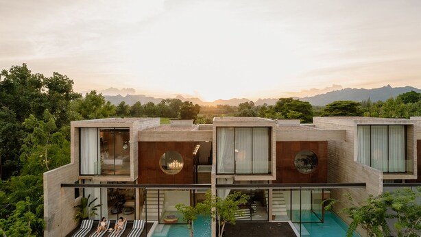 Un edificio moderno de varios pisos con piscina en la azotea, grandes ventanales y vistas a las montañas.