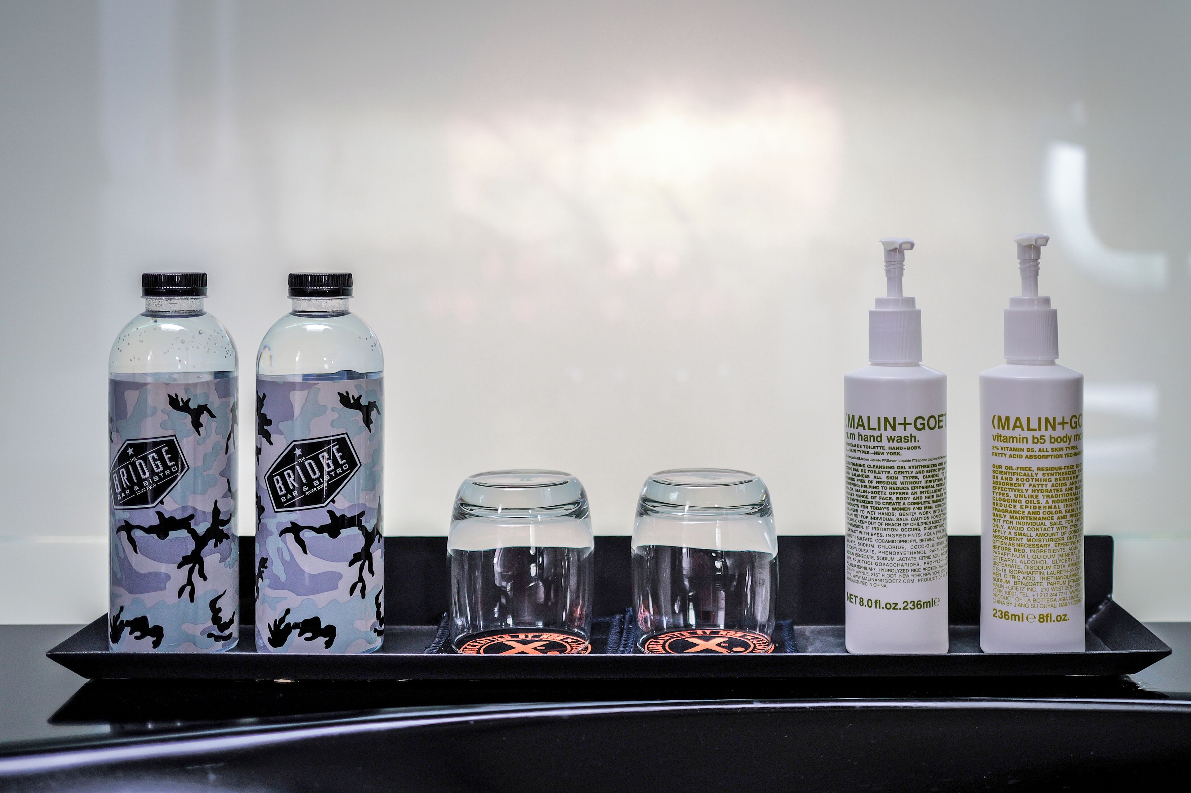 A tray with two bottles of water, two bottles of hand wash soap, and two bottles of body wash.