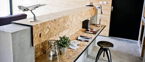 A reception desk with a wooden top, a metal lamp, a glass jar, and a potted plant.