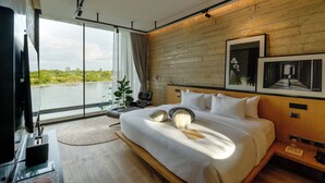 Habitación de hotel moderna con una cama grande, televisión, un panel de madera decorativo y vista a un cuerpo de agua.
