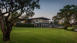 Un edificio moderno con fachada de vidrio, rodeado de céspedes y árboles bien cuidados.