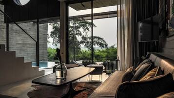 A modern interior with a sofa, dining table, and a view of greenery outside.