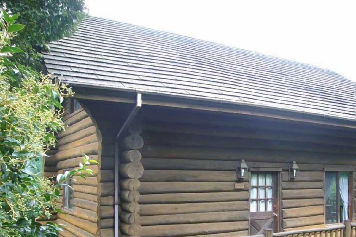 A log cabin with a wooden porch and a number sign '1707' in front.