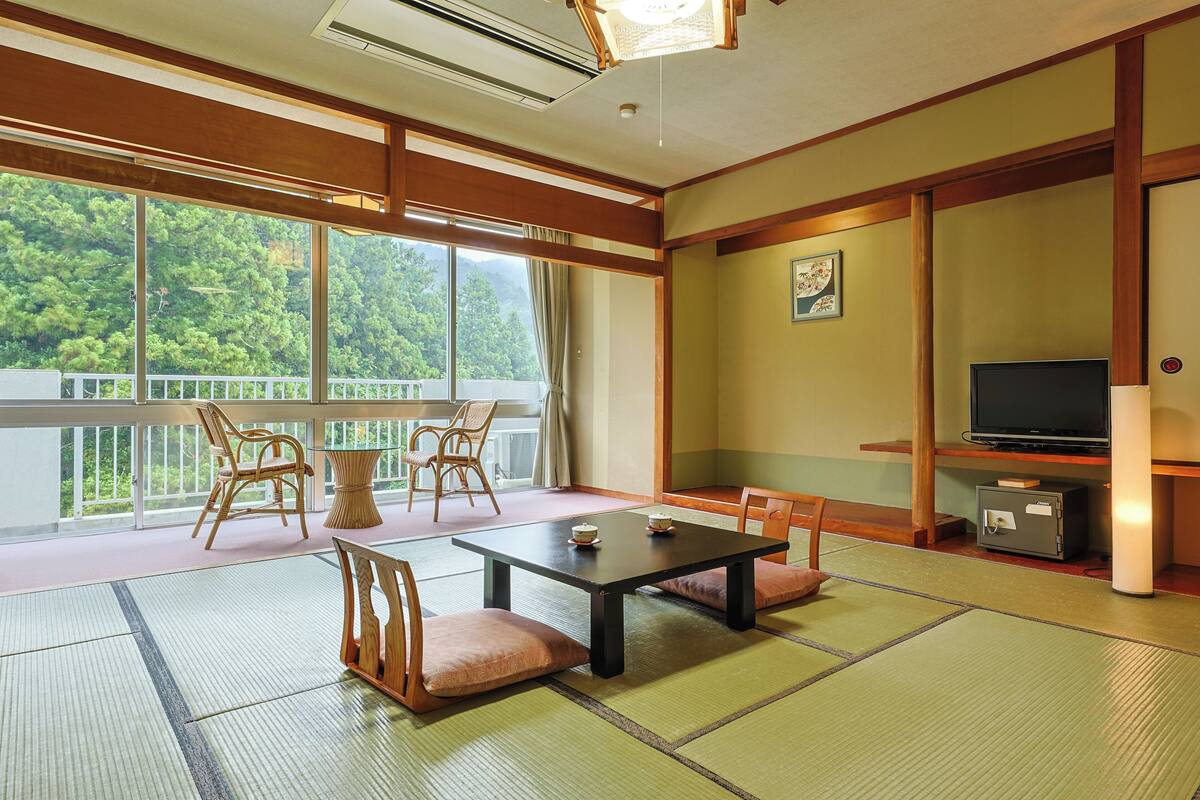 A traditional Japanese-style room with tatami flooring, a low table, and seating.