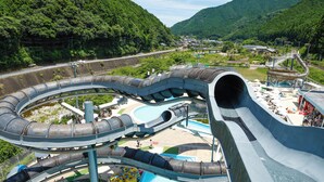 A water park with a large water slide, a pool, and a mountainous backdrop. - Hinotanionsen Misugi Resort (Tsu)