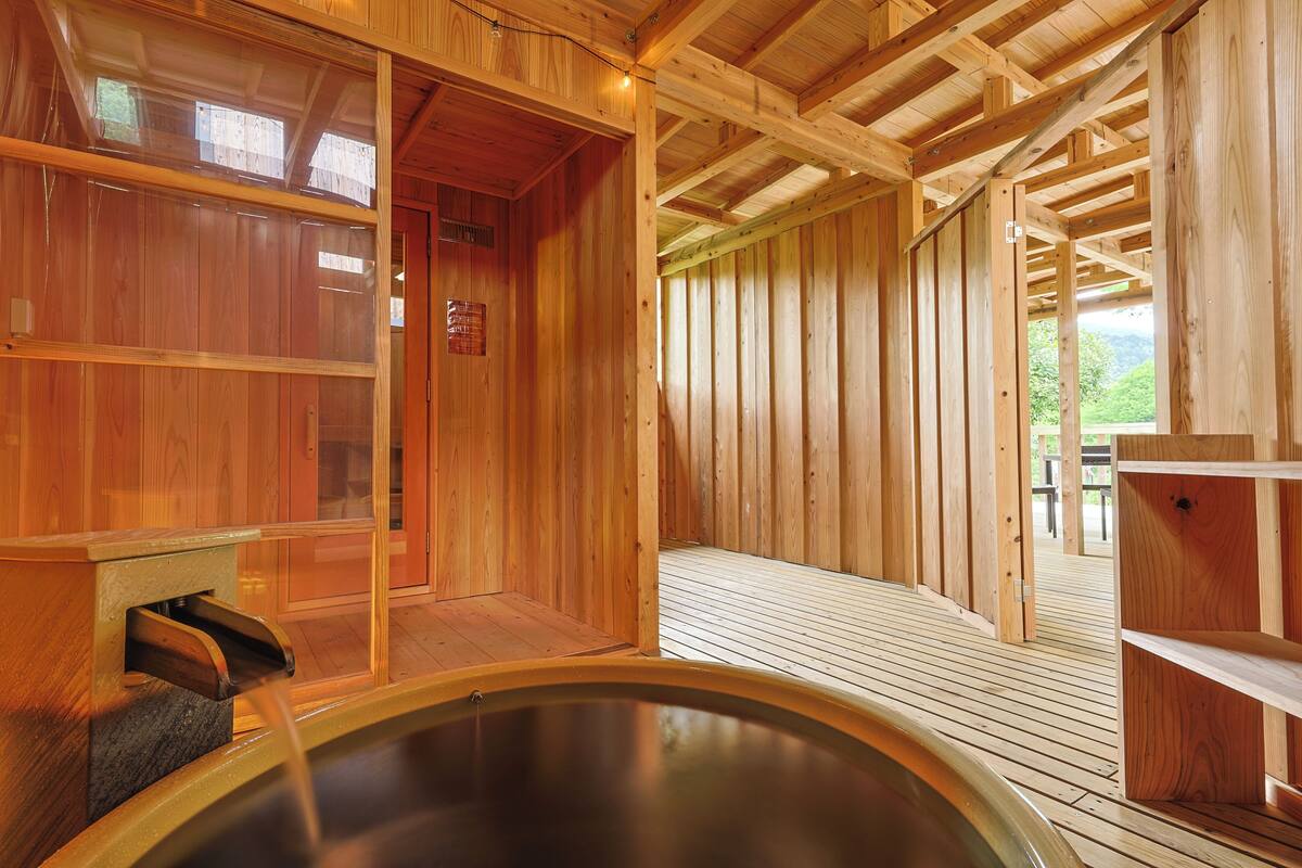 A wooden sauna with a wooden deck and a hot tub.