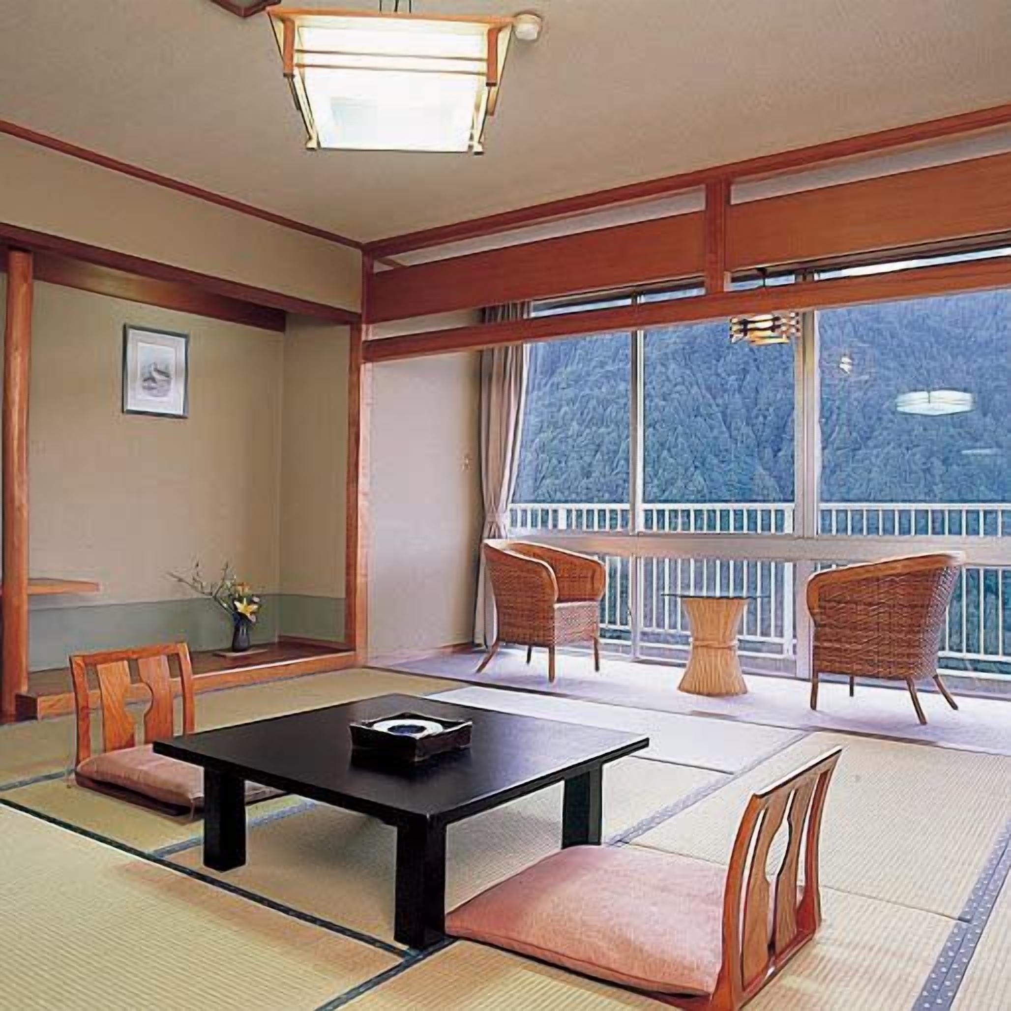 A traditional Japanese-style room with tatami flooring, a low table, and two chairs.