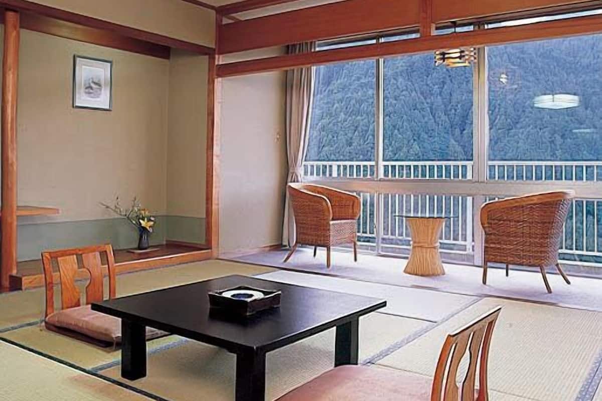 A traditional Japanese-style room with tatami flooring, a low table, and two chairs.