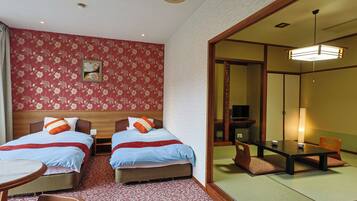 A hotel room with two beds, a dining table, and a traditional Japanese-style room.