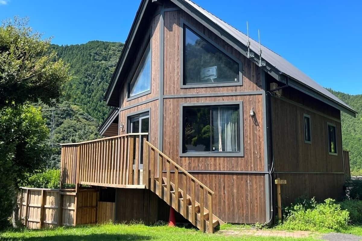 Une maison en bois à deux étages, dotée d’un balcon, de grandes fenêtres et d’un toit à forte pente.