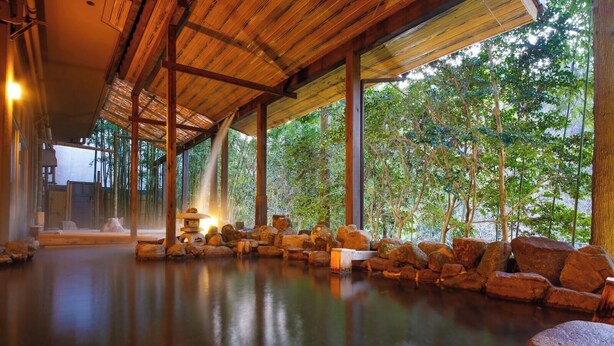 A serene indoor space with a wooden ceiling, a stone water feature, and a view of lush greenery outside. - Hinotanionsen Misugi Resort (Tsu)