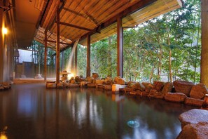 A serene indoor space with a wooden ceiling, a stone water feature, and a view of lush greenery outside. - Hinotanionsen Misugi Resort (Tsu)