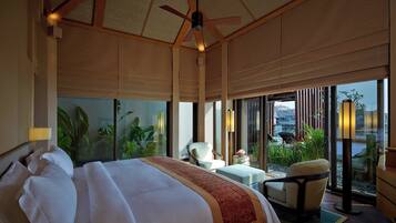 A spacious bedroom with a large bed, a ceiling fan, and a view of a balcony with plants.