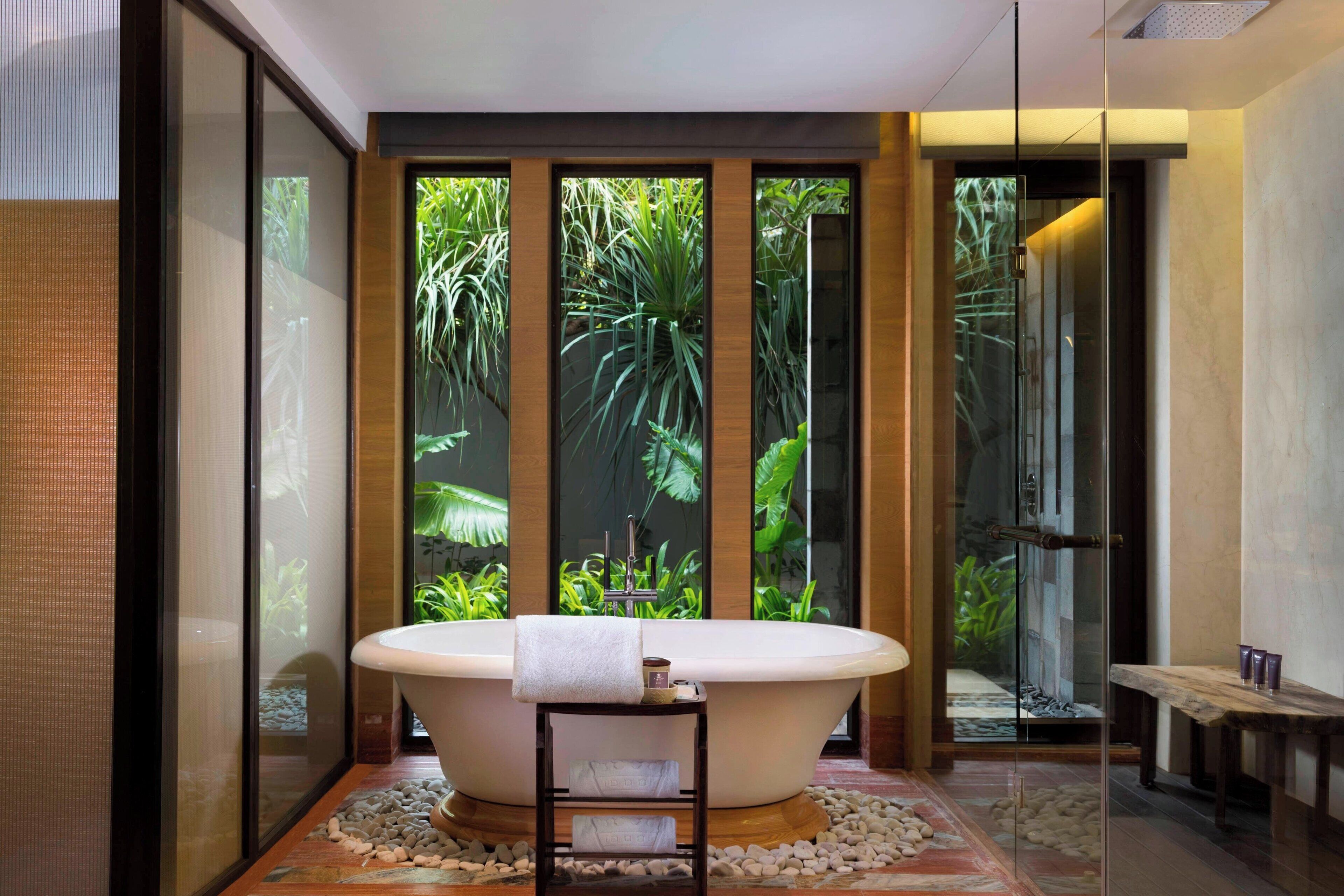 A modern bathroom with a freestanding bathtub, a wooden bench, and a glass shower enclosure.