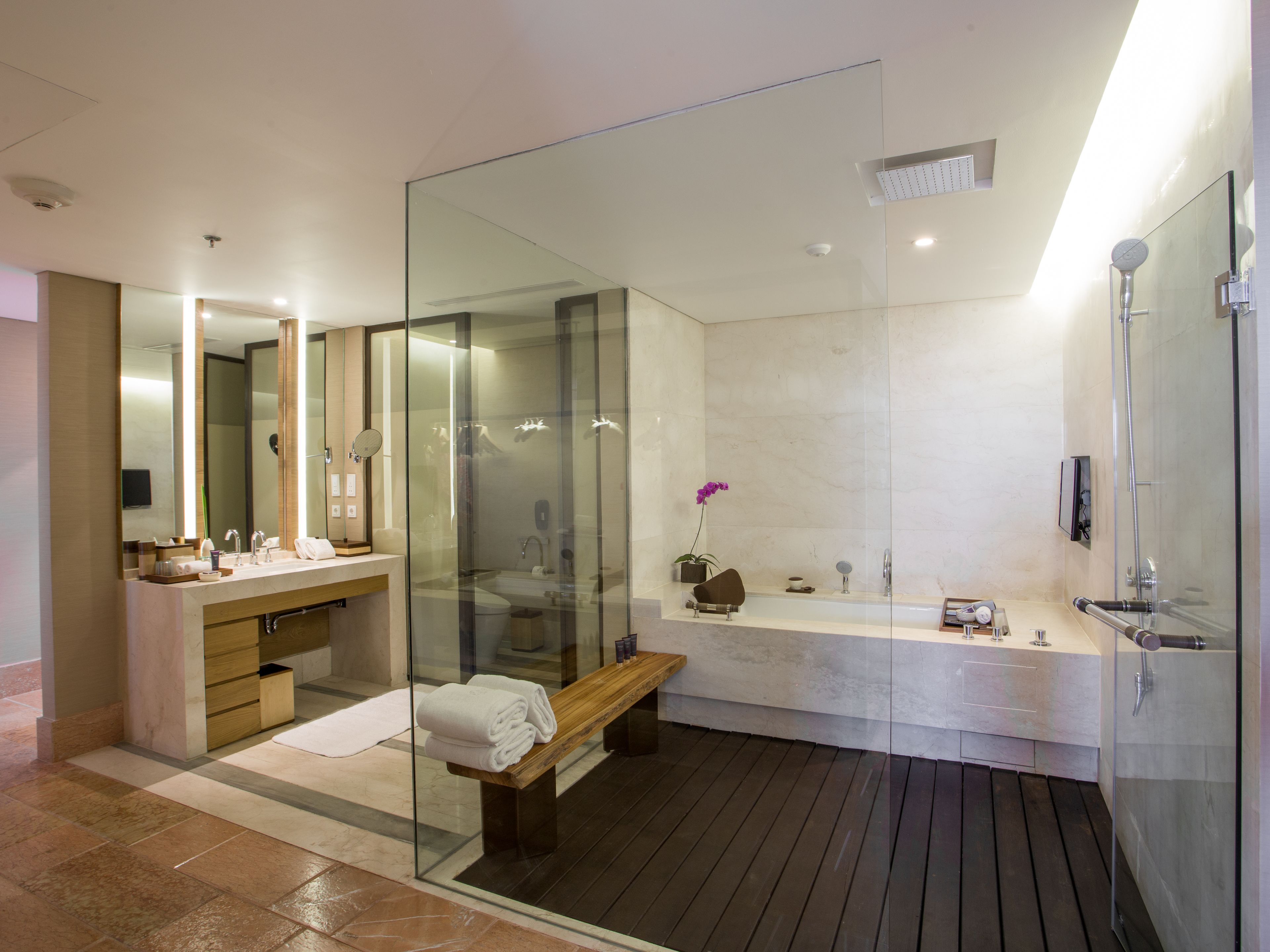 Une salle de bain moderne avec une douche à parois de verre, un banc en bois et un grand miroir.