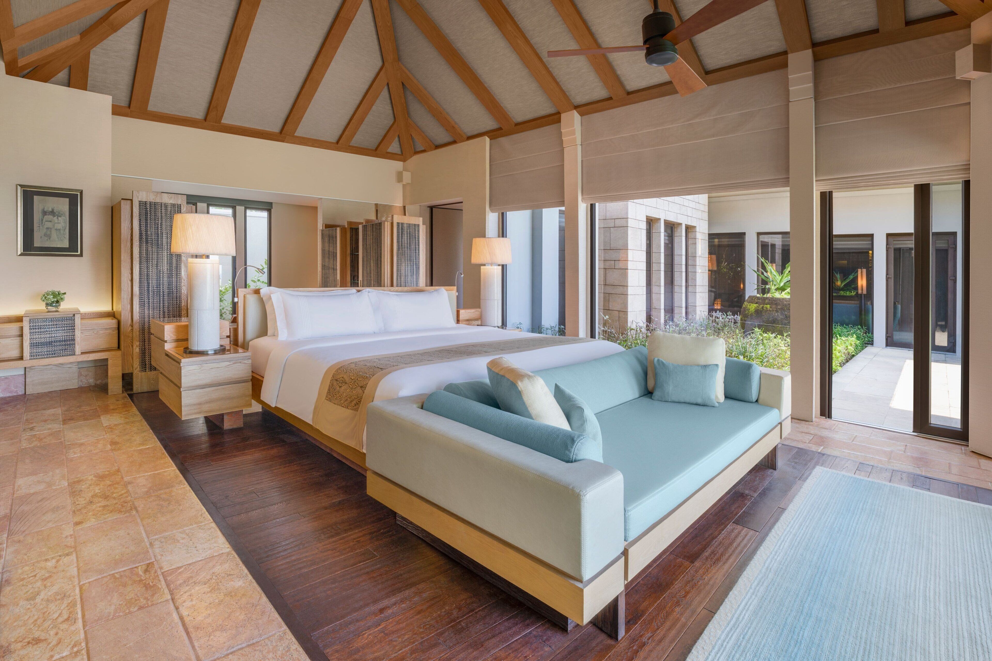 A spacious bedroom with a large bed, a sofa, and a view of the outdoors.