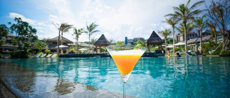 A cocktail glass with a tropical drink on a poolside ledge.