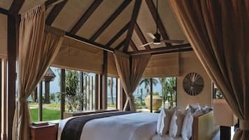 A spacious bedroom with a large bed, wooden beams, and a view of the ocean.
