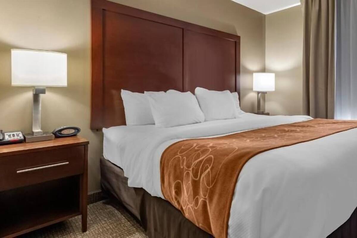 A hotel room with a bed, bedside tables, lamps, and a window with curtains.