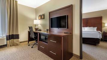 A hotel room with a bed, a desk with a computer, a television, and a microwave.