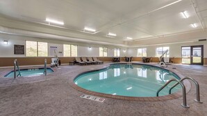 Una amplia piscina cubierta con varias pistas, tumbonas y un área de spa.