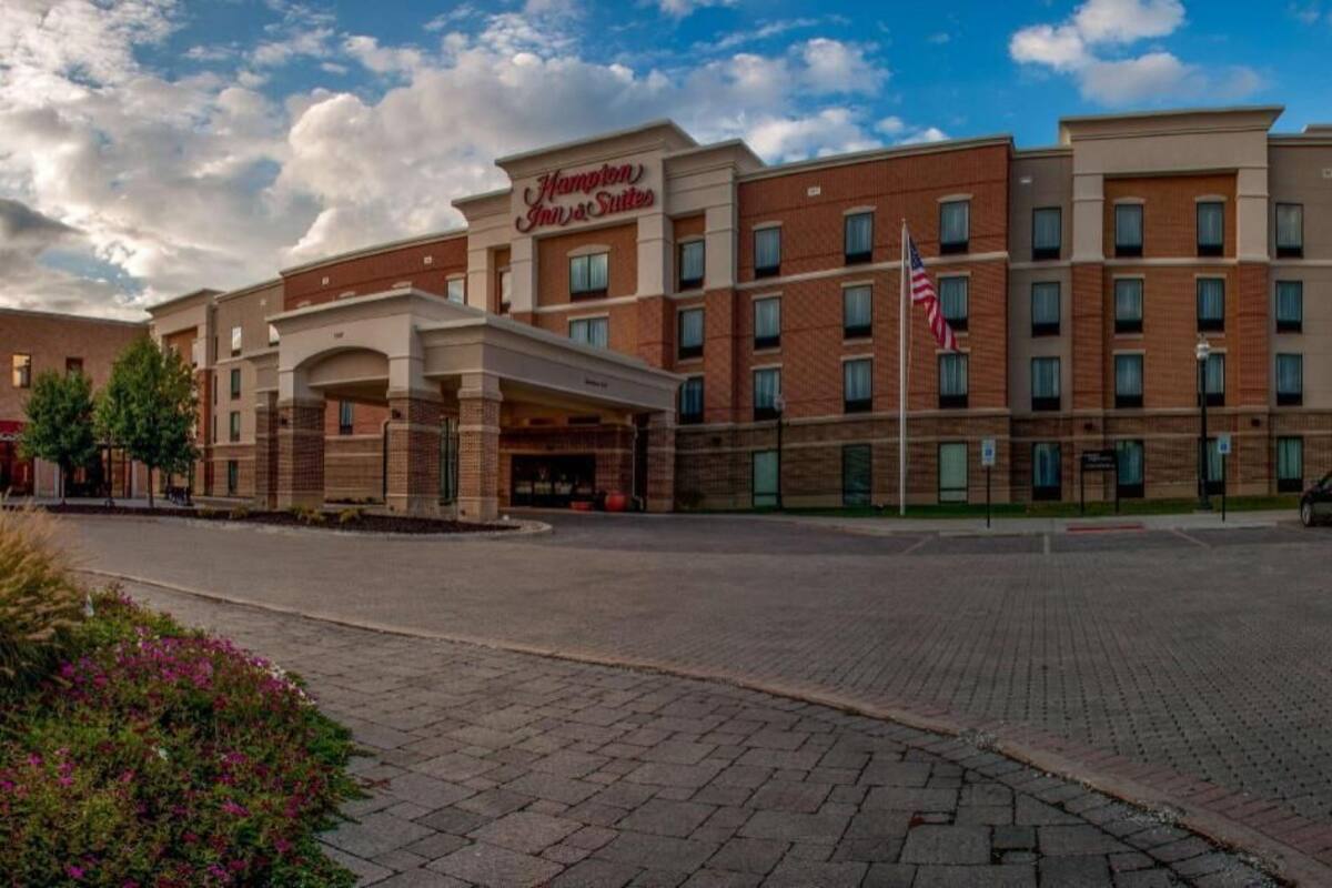 A Hampton Inn & Suites hotel with a brick facade, multiple floors, and a covered entrance.