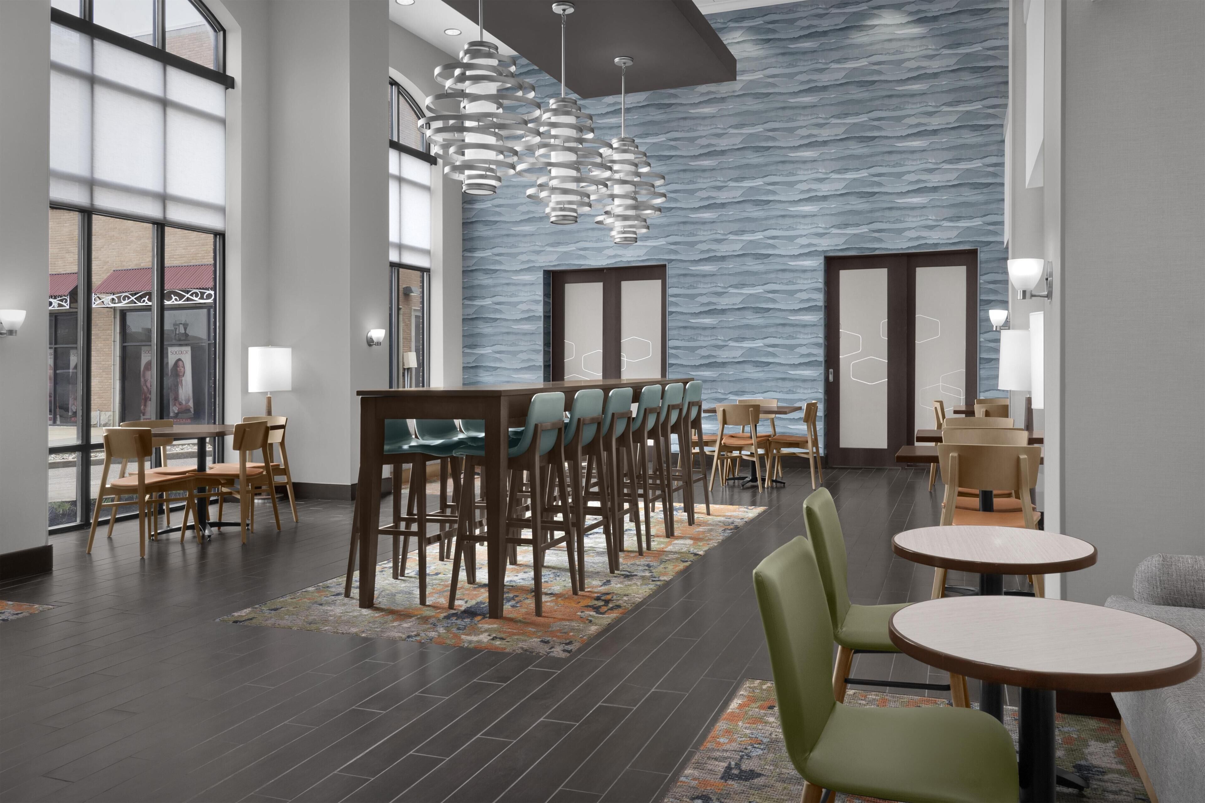 A modern hotel lobby with a bar area, seating arrangements, and a patterned wall.