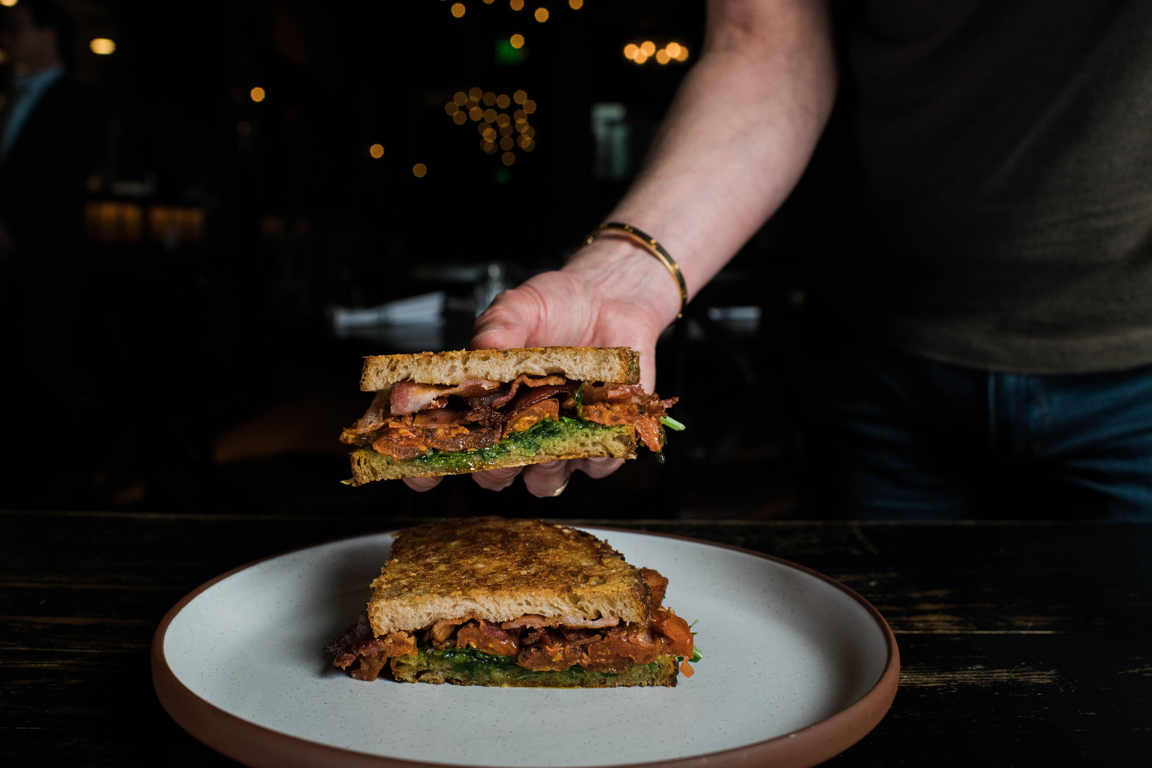 Un sandwich sur une assiette, qu’une personne tient au-dessus de l’assiette.