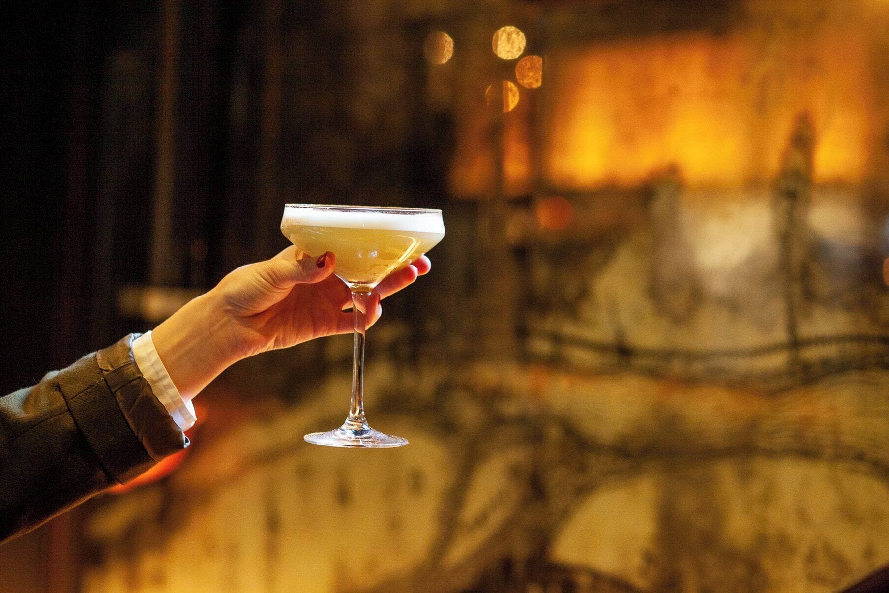 A hand holding a cocktail glass with a blurred background.