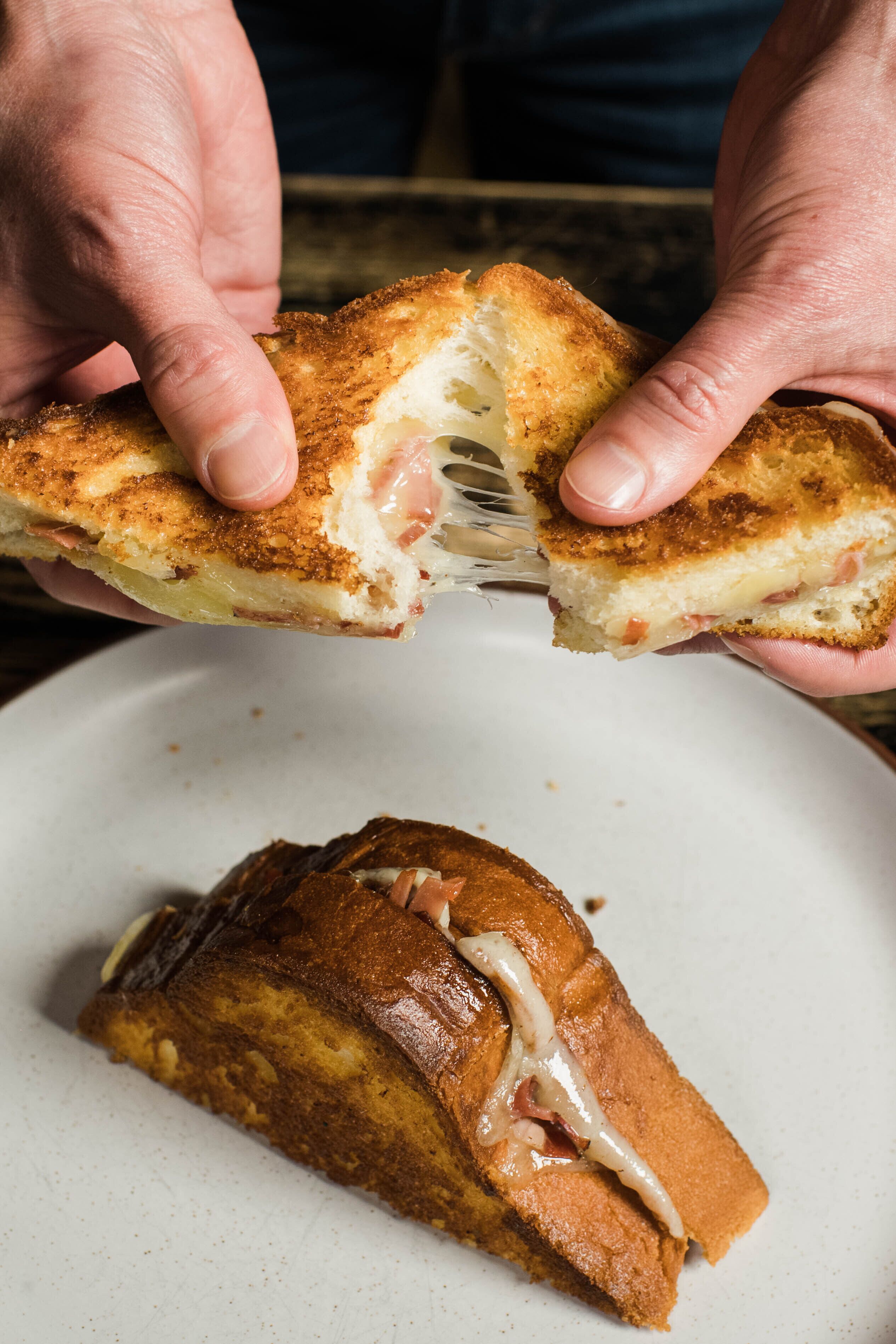 A person holding a grilled sandwich with visible fillings.