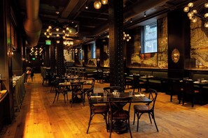 A restaurant interior with wooden floors, multiple dining tables, and hanging spherical light fixtures. - Kimpton Hotel Monaco Pittsburgh by IHG (Pittsburgh)