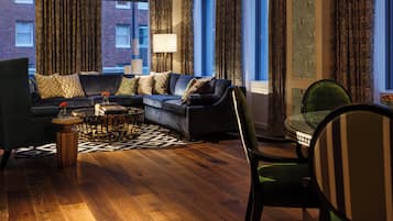A modern living room with a dark blue sofa, patterned curtains, and a view of a brick building.
