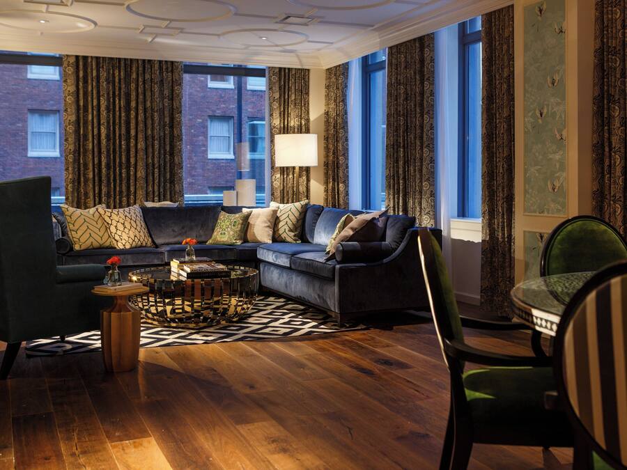A modern living room with a dark blue sofa, patterned curtains, and a view of a brick building.