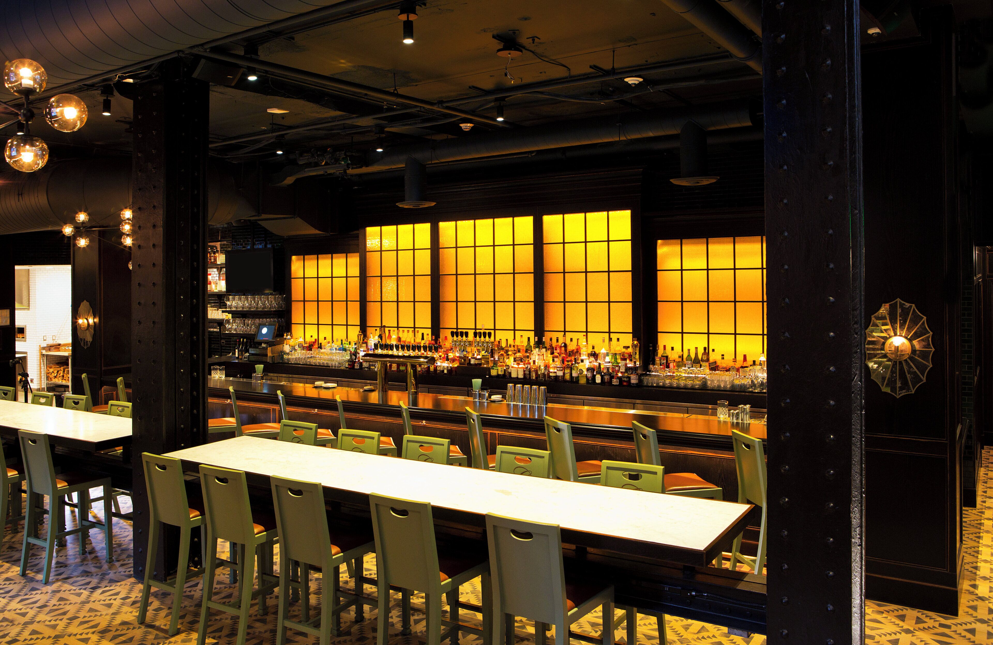 Een restaurant met een bar, meerdere tafels en stoelen.