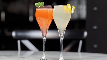 Two glasses of cocktails on a marble surface with a blurred background.