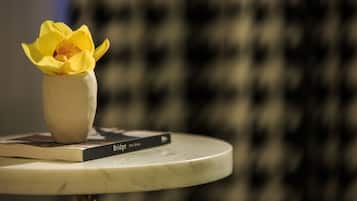A white vase with a yellow flower on a round table, with a book titled "Bridge" beside it.