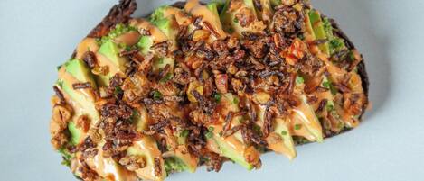 A dish with avocado, bacon, and a creamy sauce.