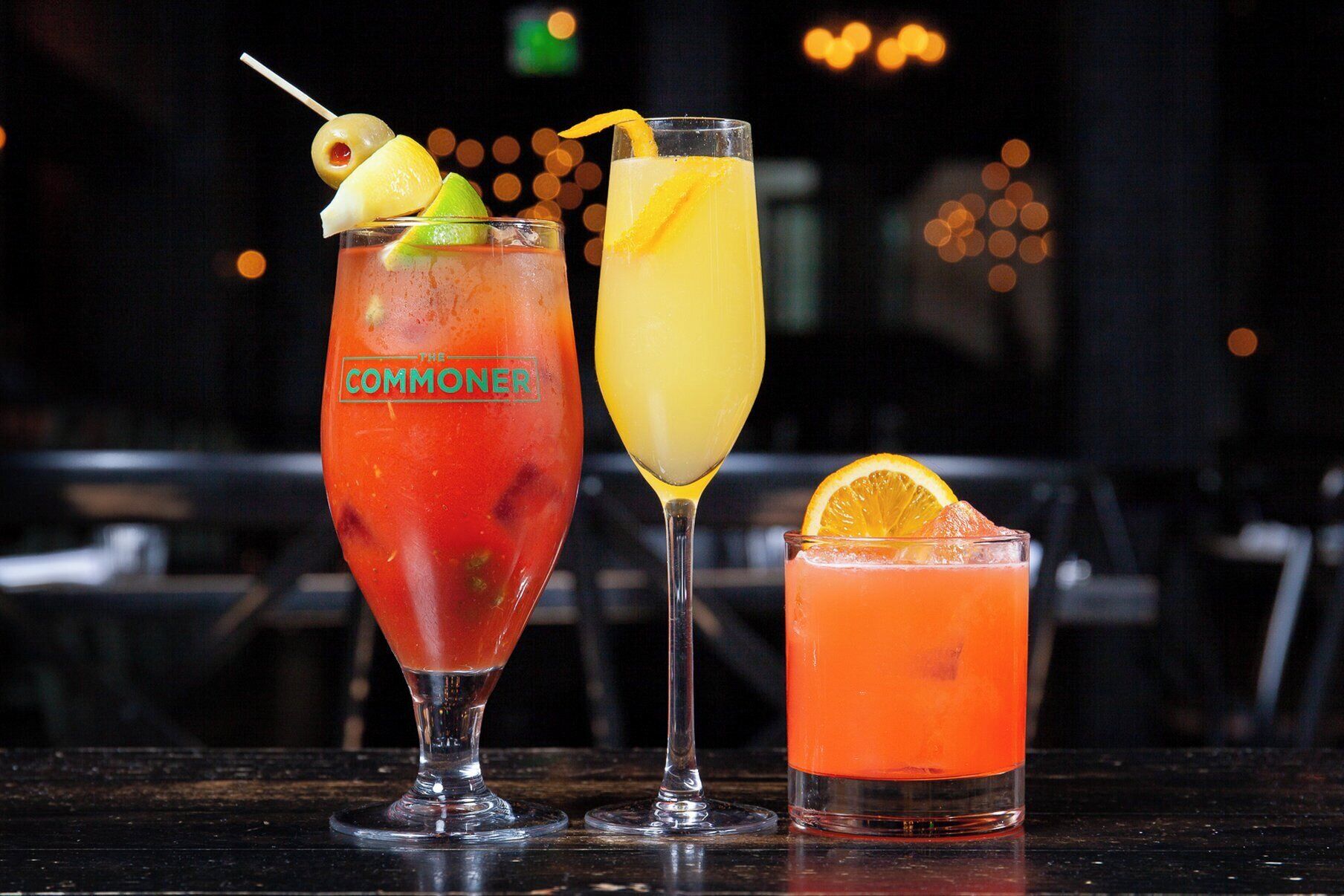 Three glasses of cocktails on a bar counter.